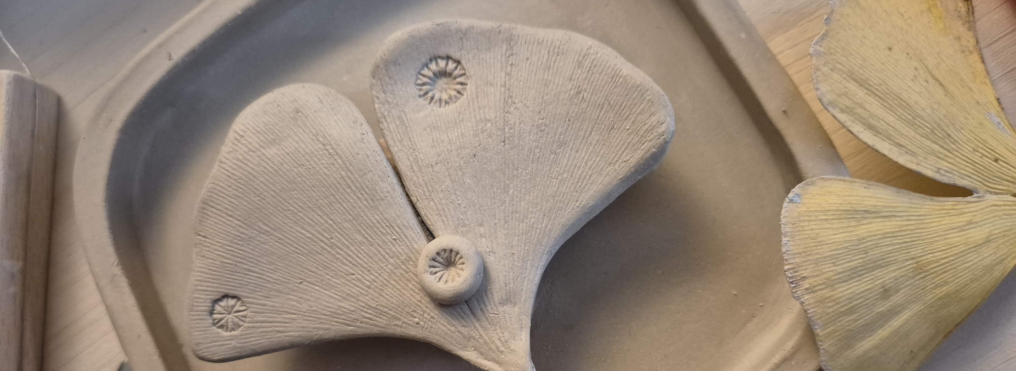 Schlichte, keramische Form mit einem zarten gelben Ginkgoblatt im Hintergrund.